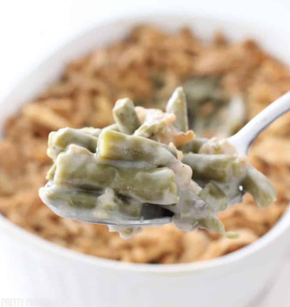 Spoonful of Green Bean Casserole close up, with the rest of the dish behind it. 