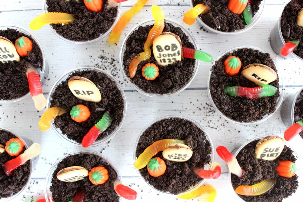 birds eye view of a bunch of Halloween dirt cups lined up on a wooden backdrop