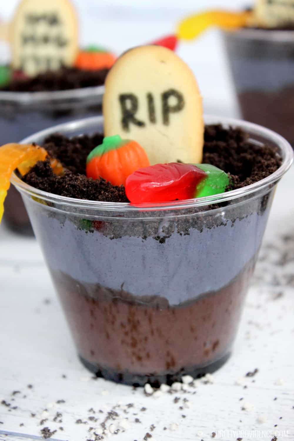 close up photo of a layered oreo pudding dirt cup with a cookie tombstone
