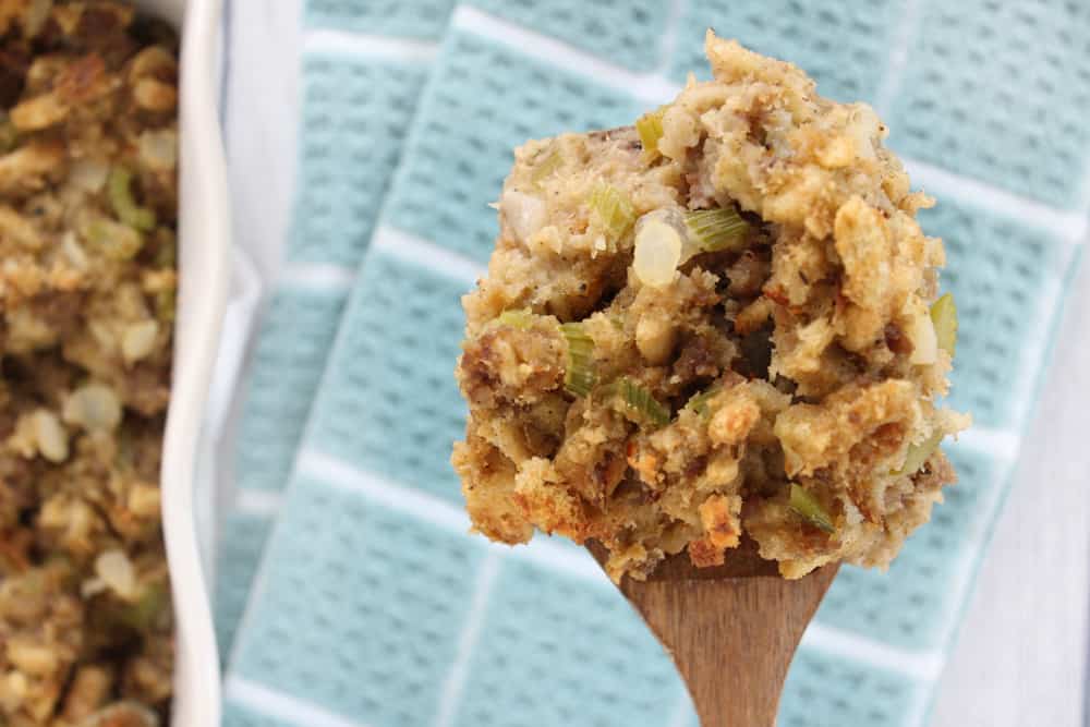 Close up spoon full of stuffing with sausage, celery, herbs in it.