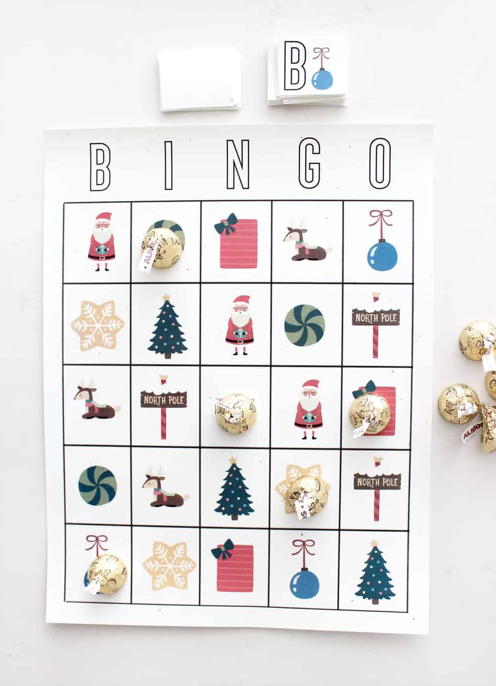 A Christmas Bingo card with chocolate kiss markers covering some of the squares.