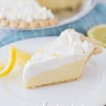 a slice of lemon sour cream pie on a white plate with a blue cloth underneath