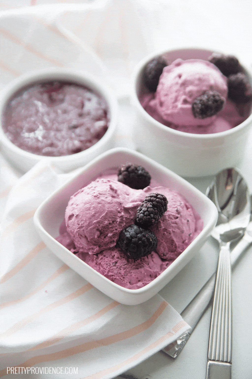Homemade blackberry ice cream served in white dishes next to a spoon. 