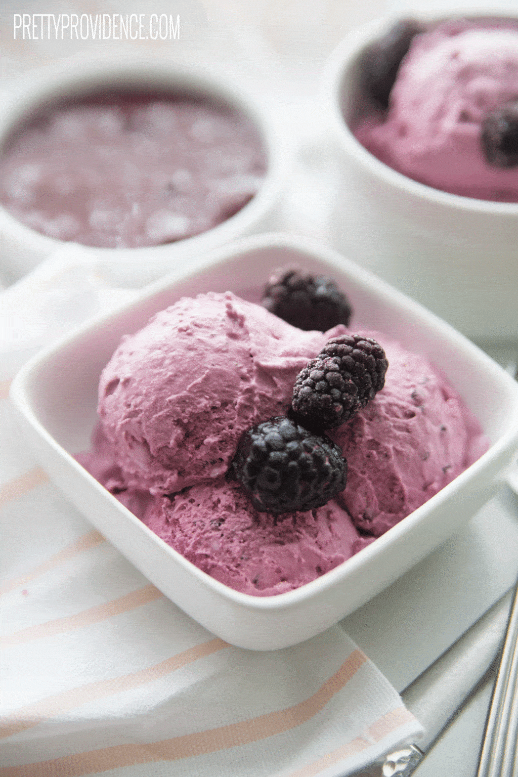 Small dish of homemade blackberry ice cream with fresh fruit on top.