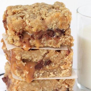 Carmelitas, layered oatmeal chocolate and caramel dessert bars, with a glass of milk on the side.