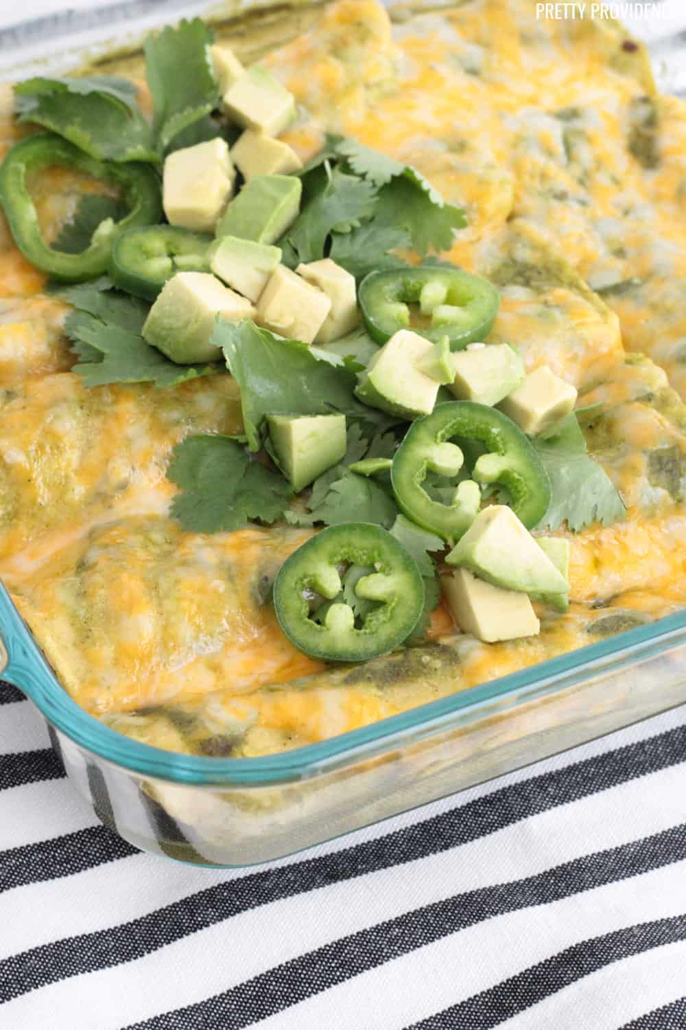 Green Beef Enchiladas in a glass dish, topped with cheese, jalapeños, avocado and cilantro.