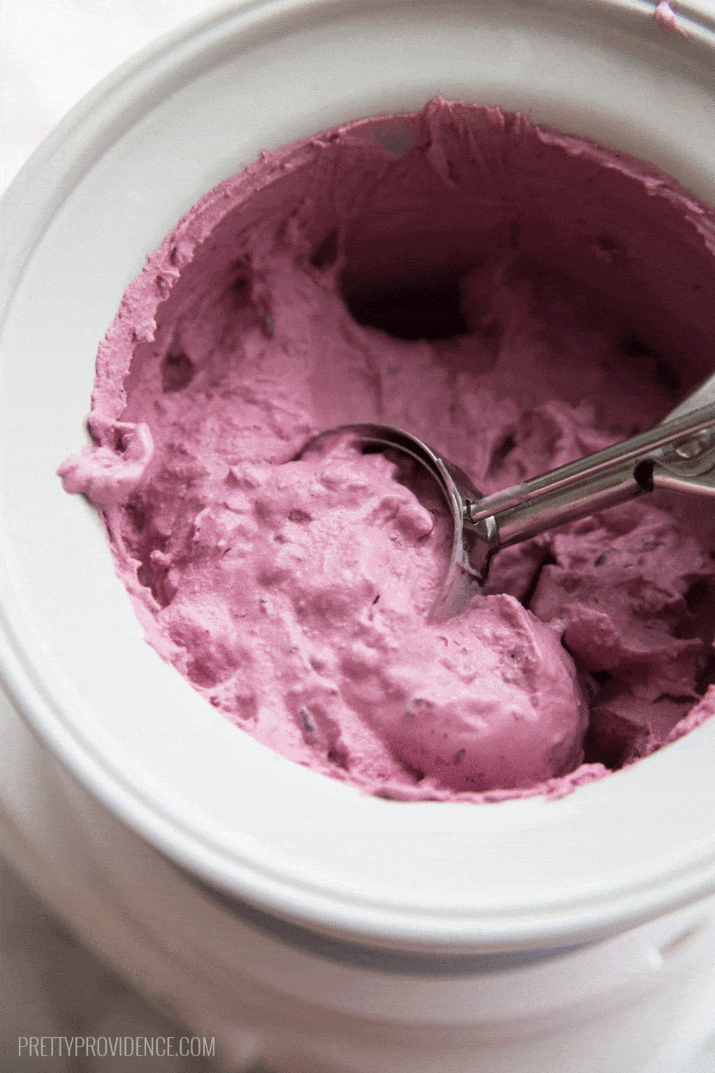 Scooping a scoop of fresh blackberry ice cream out of the ice cream maker.