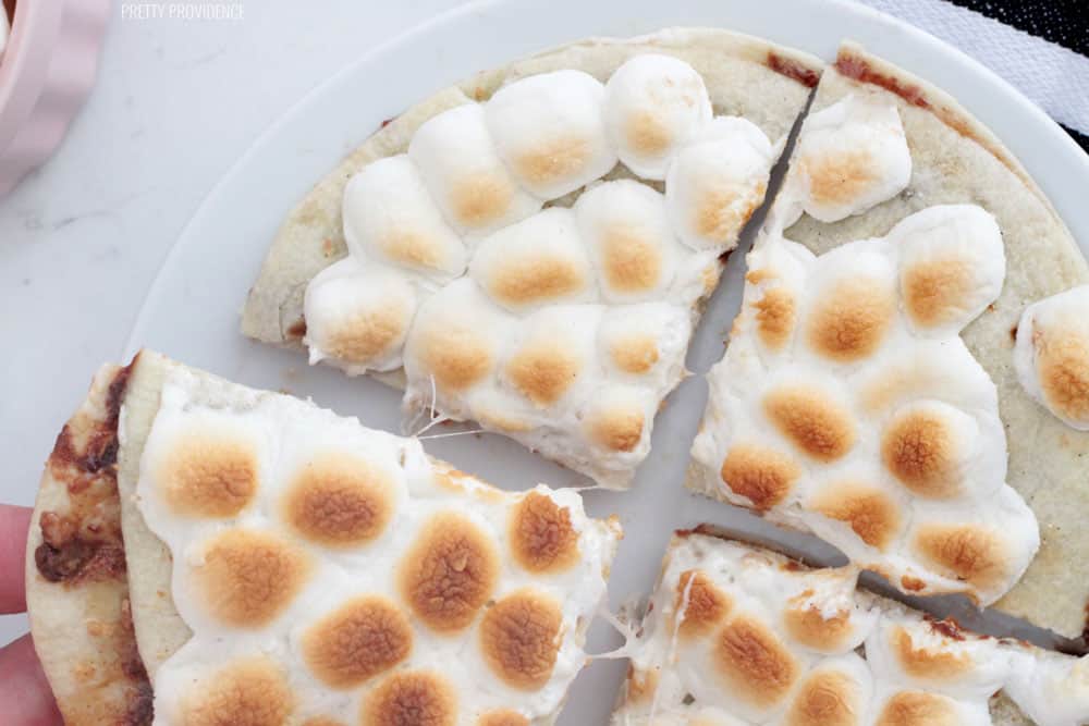 Dessert Quesadilla covered in toasted marshmallows on a white plate, cut into four triangles..