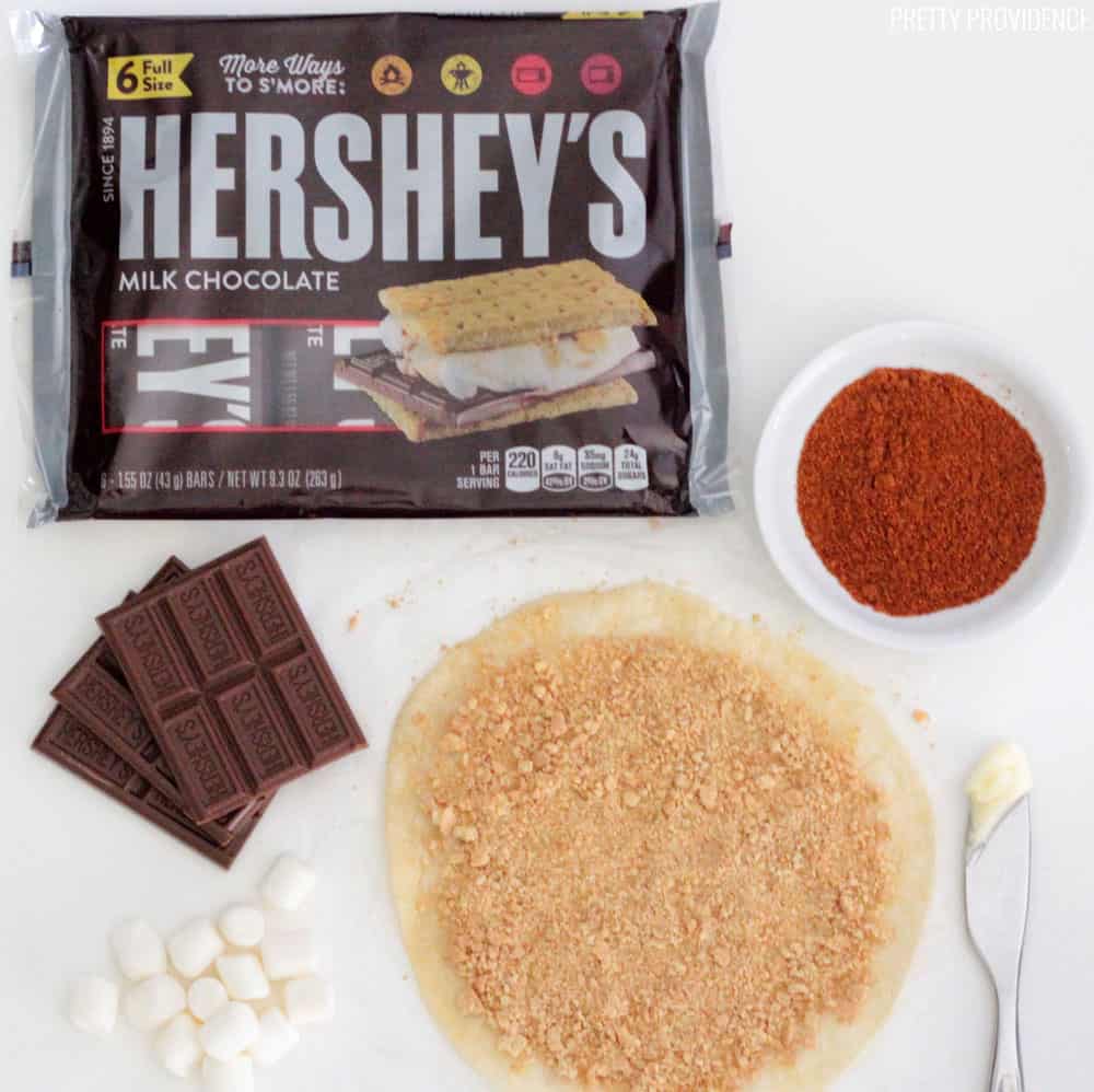 Tortilla covered in graham cracker crumbs, with marshmallows, Hersheys bars and cayenne pepper surrounding it.