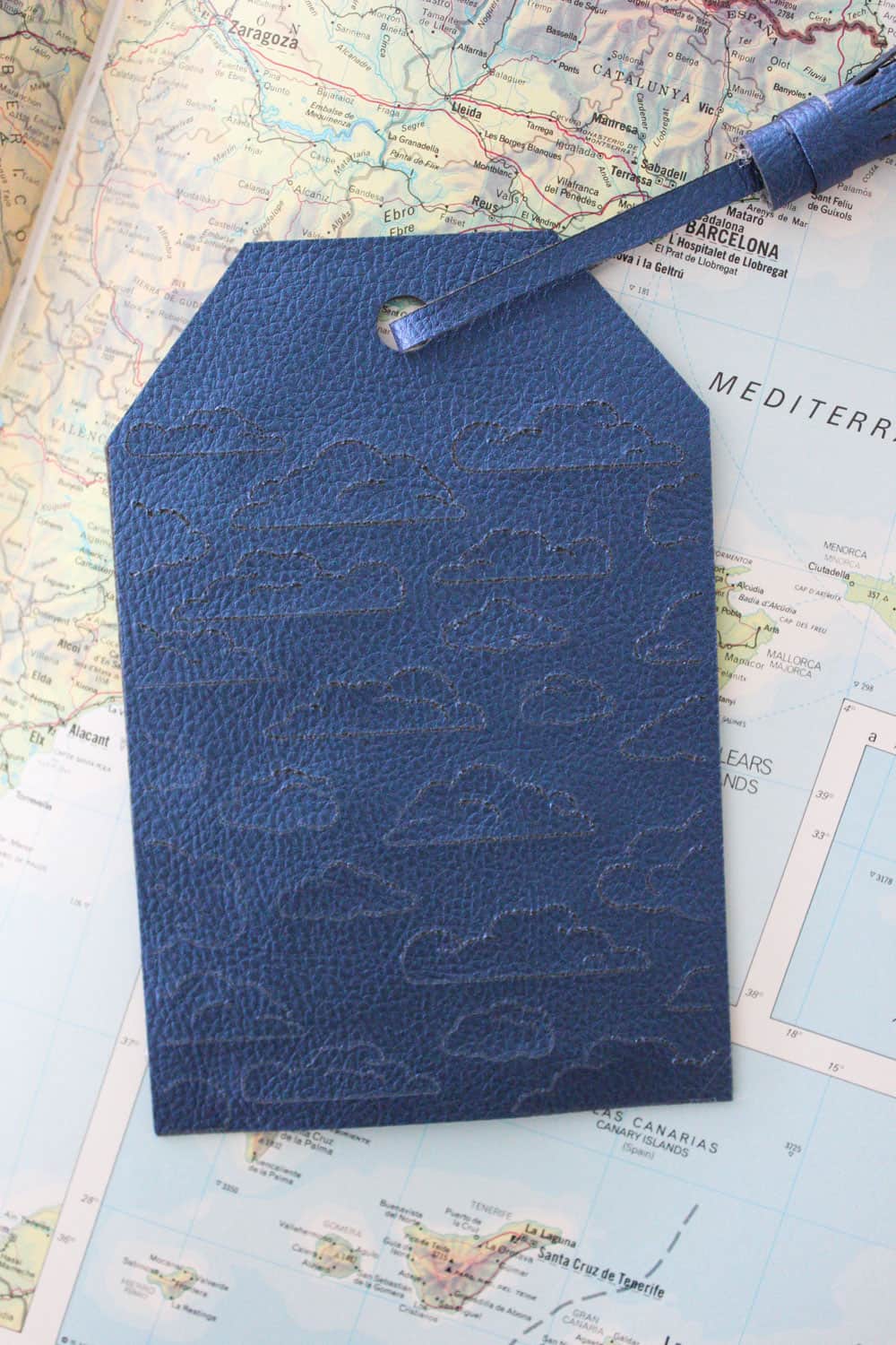 finished blue luggage tag with clouds engraved on it