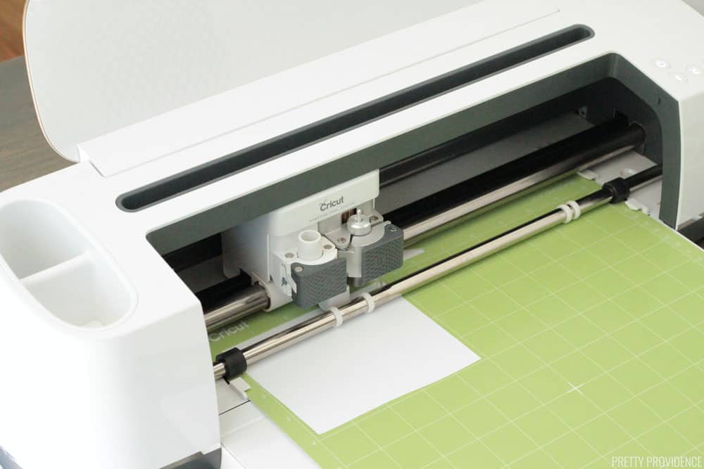 Cricut Maker machine with a green Standard Grip mat in it, cutting a small sheet of iron-on vinyl.