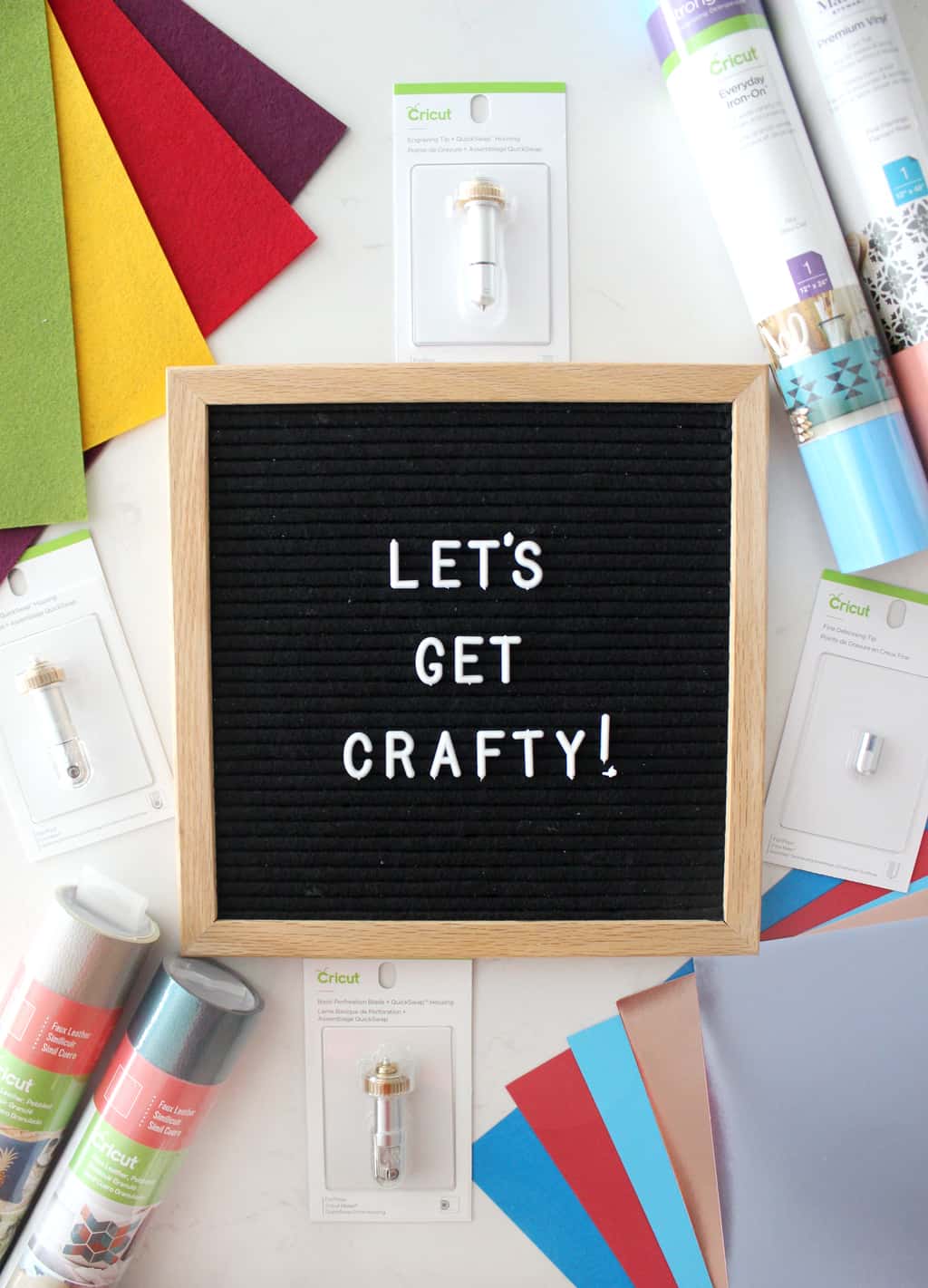 an assortment of craft supplies surrounding a letter board that says "let's get crafty" 