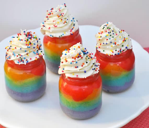 For mini rainbow cakes made in repurposed baby food jars with white frosting on top and rainbow sprinkles