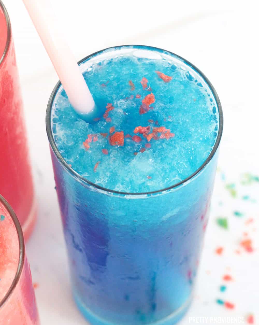 Blue sonic slush with pop rocks on top in a tall glass with a pink straw.