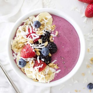 fresh berry smoothie bowl on a white counter with fresh fruit