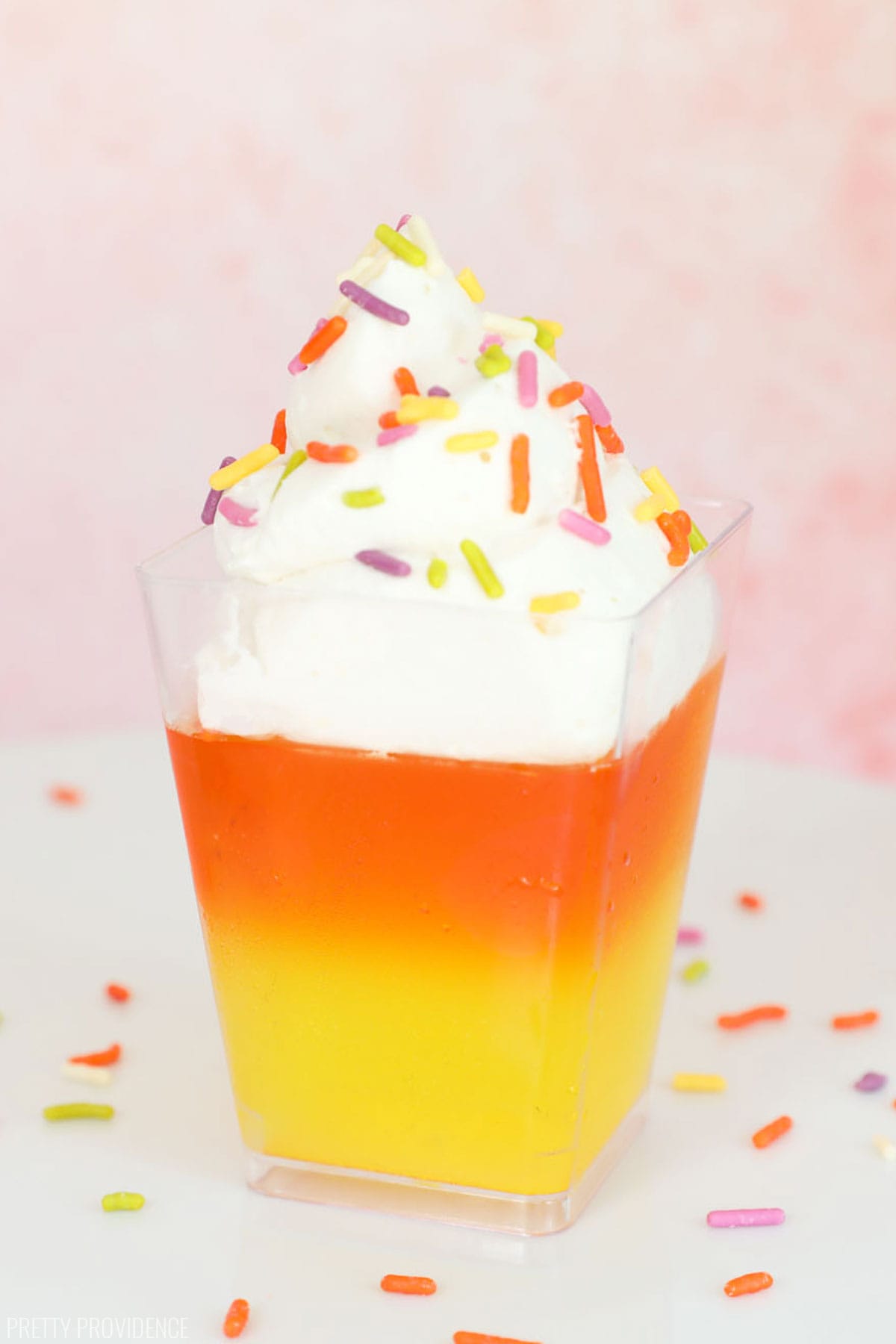 Candy corn Jello cup for Halloween. Yellow later, orange layer and cool whip with orange and yellow sprinkles on top.