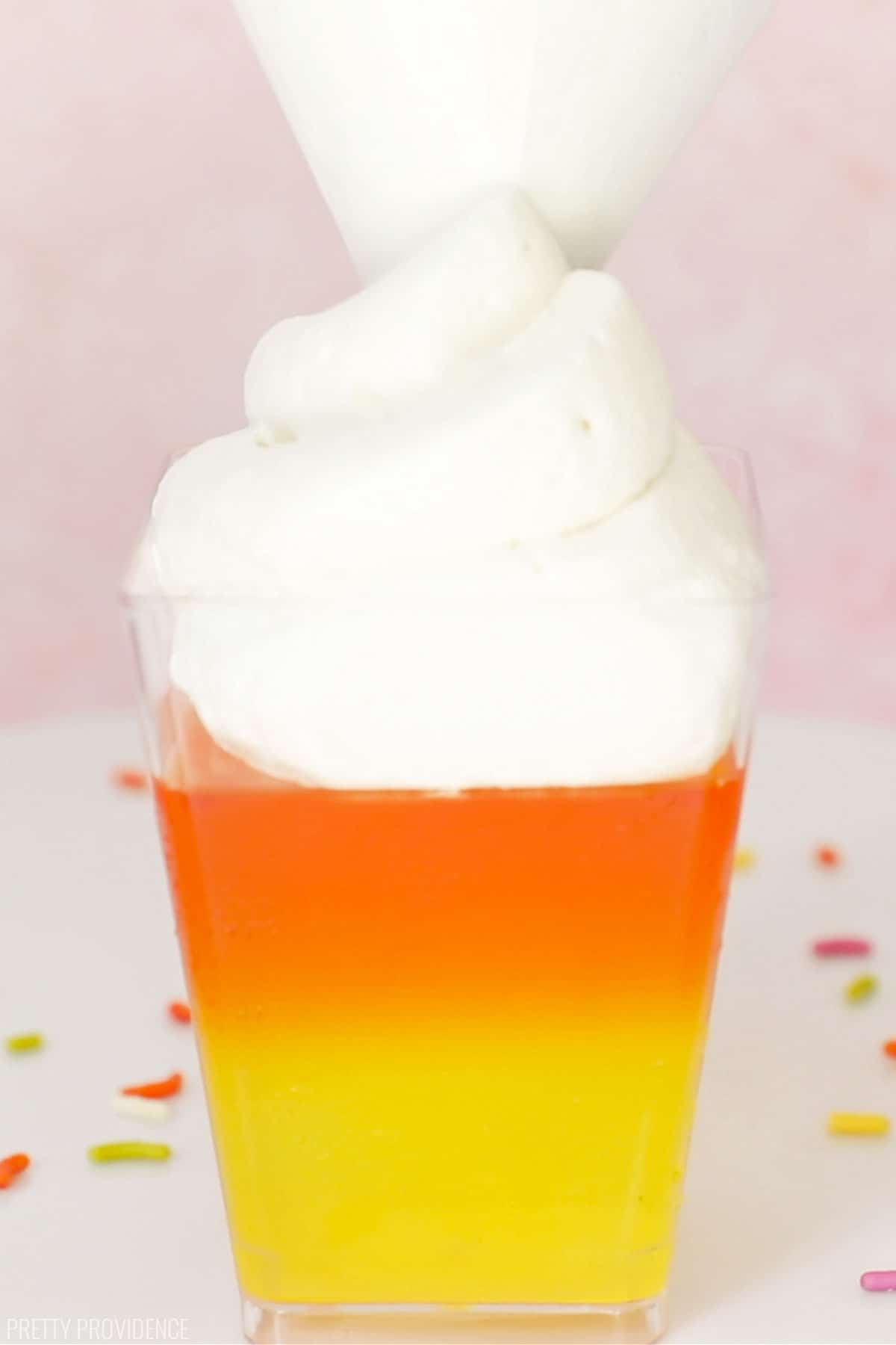 Candy corn Jello with yellow layer, orange layer on top of that and then cool whip being piped onto the top.