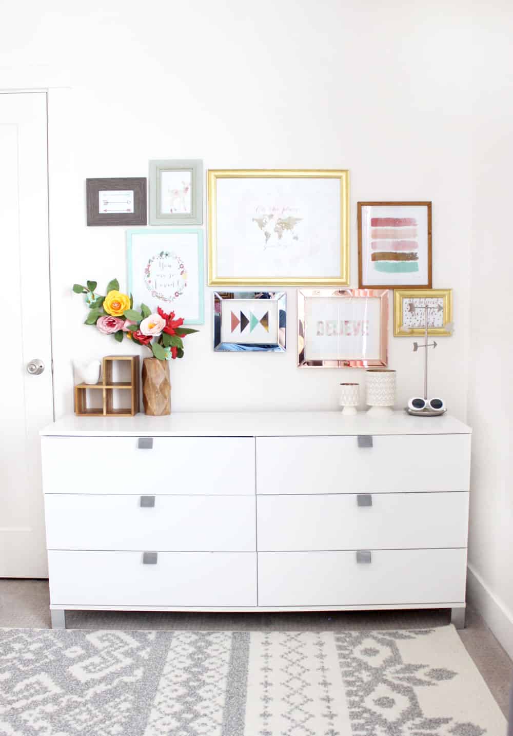 a modern white dresser underneath a colorful gallery wall