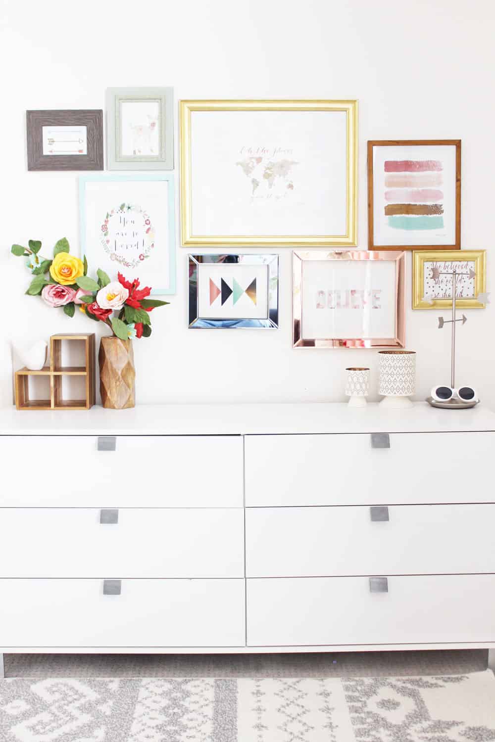 white dresser with a colorful gallery wall laid out above it. 