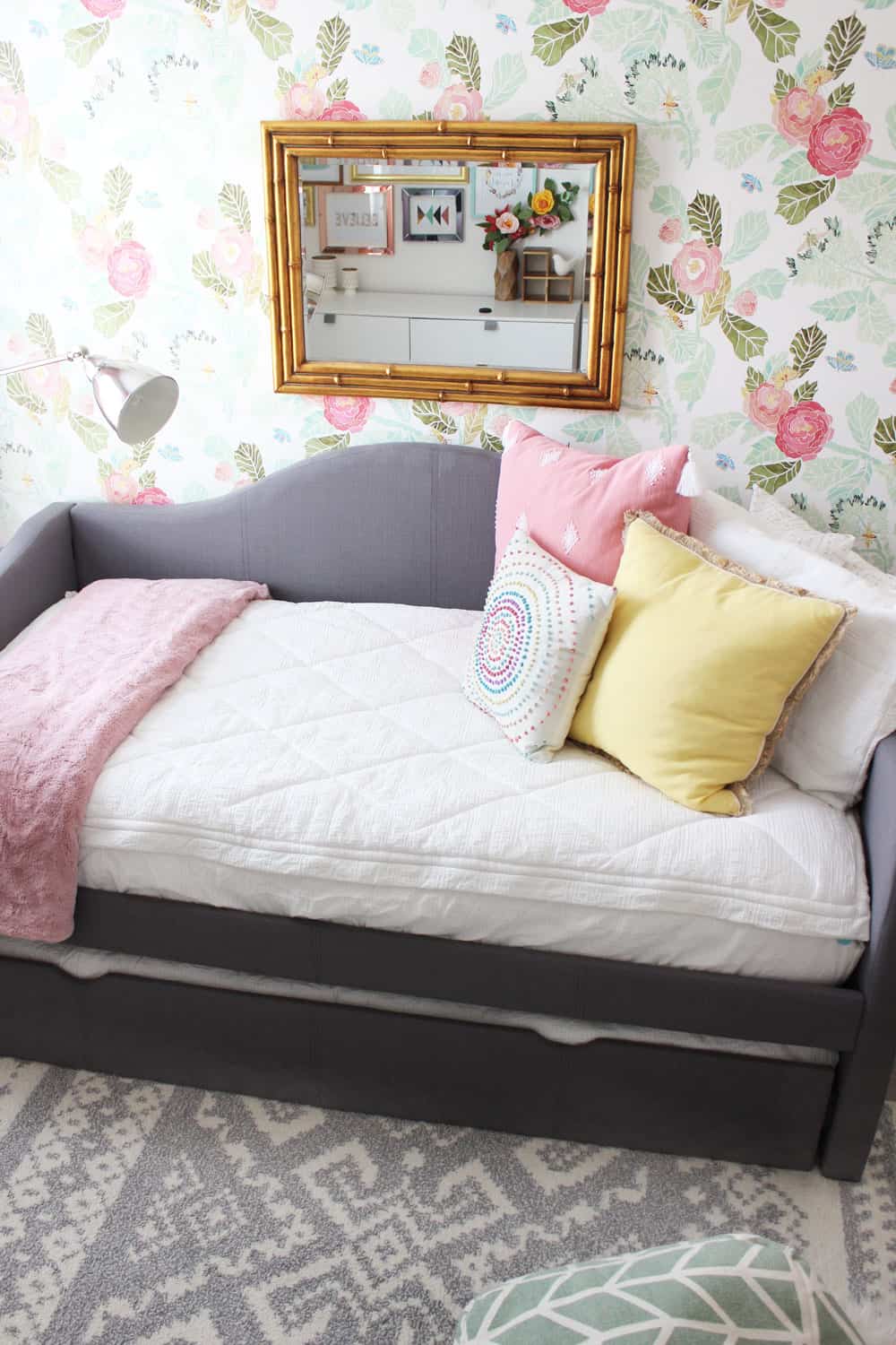 girls room with bed against a floral wall and grey tribal rug