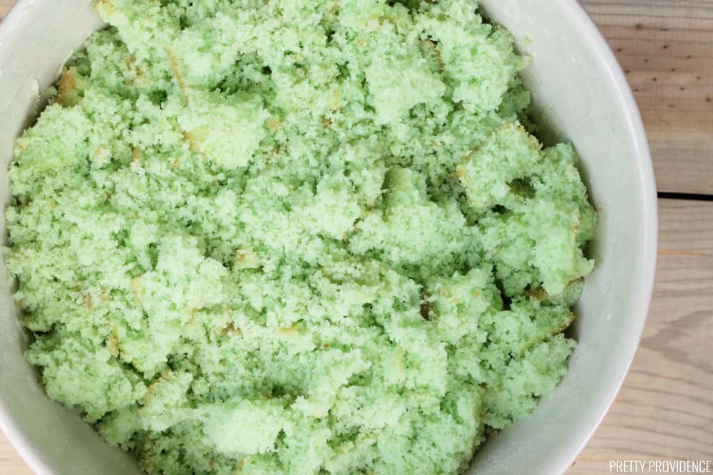 Green cake broken up into crumbs in a bowl.