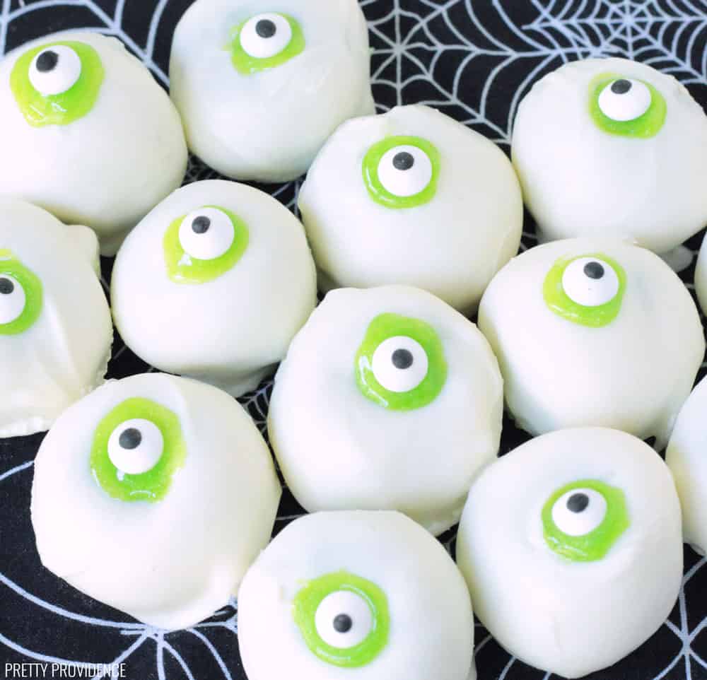 Halloween Cake Balls that look like Eyeballs. Green cake dipped in white candy, green icing and candy eyeballs.