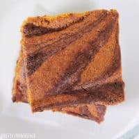 Square Pumpkin Brownies swirled stacked on a white plate.
