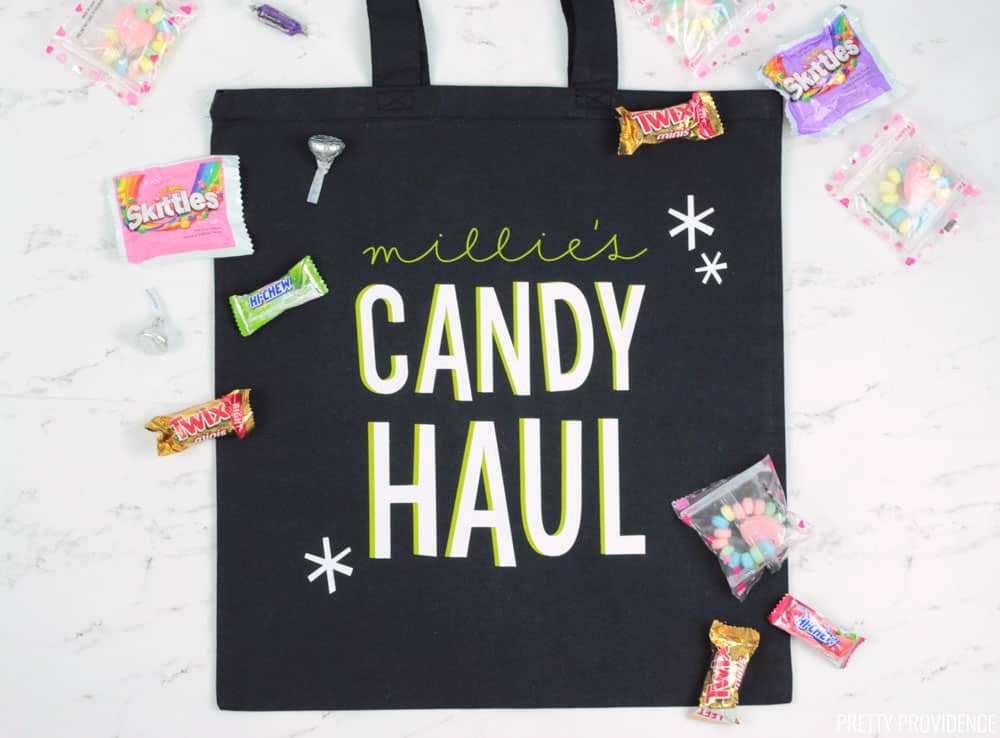 Candy Haul trick or treat bag made with a black tote bag and iron-on, with Halloween candy surrounding the bag.