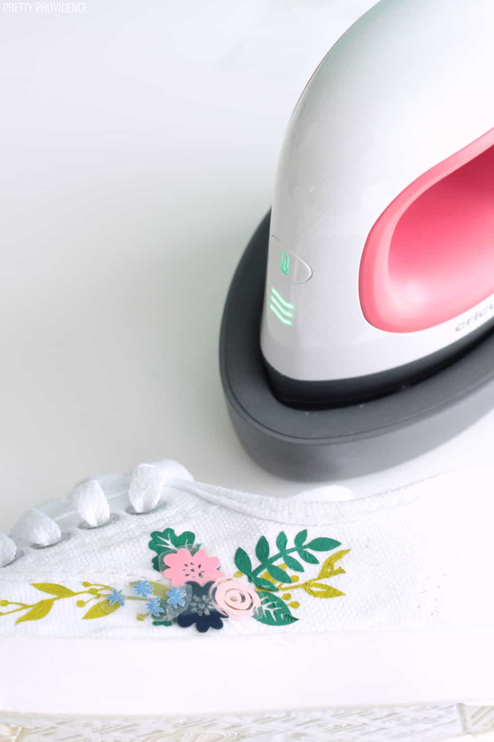 EasyPress Mini (mini craft iron made by Cricut) and a white keds shoe with iron-on vinyl being applied to it.