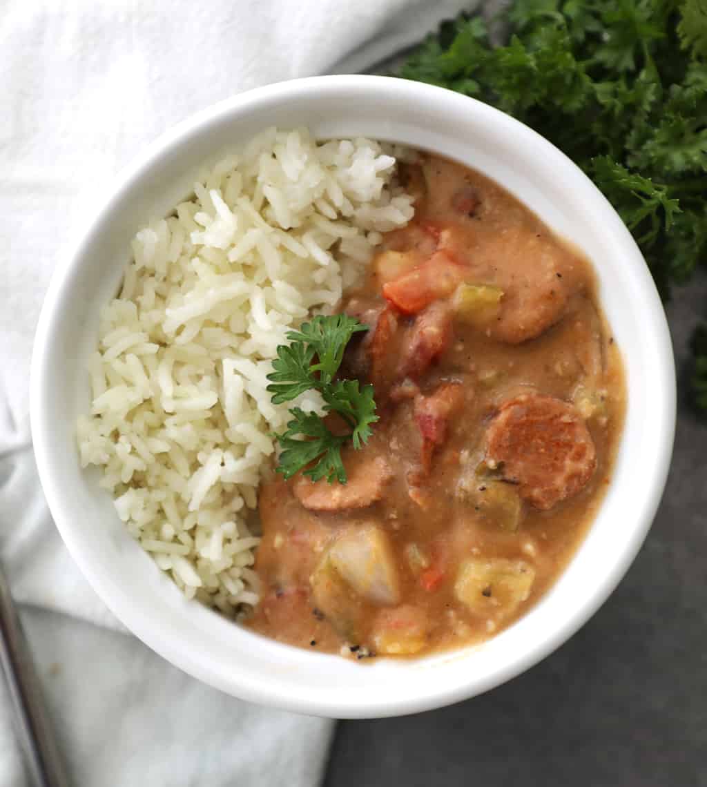 gumbo and rice garnished with fresh parsley on a concrete counter with a spoon