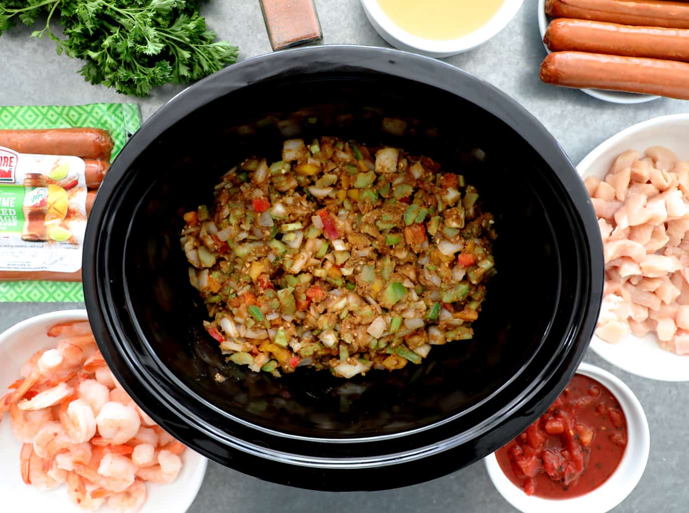 roux and veggies in crockpot surrounded by remaining gumbo ingredients 