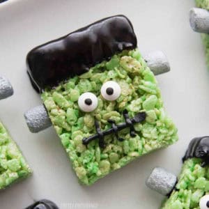 Green rice krispie treat frankenstein with candy eyeballs, black frosting hair and stitches.