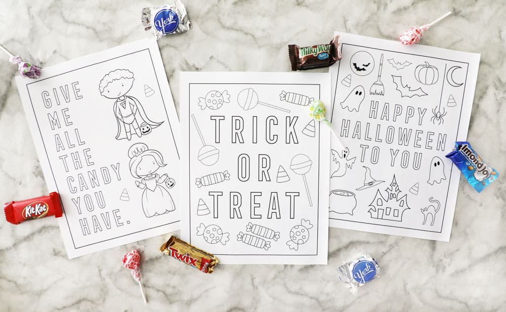 three blank halloween coloring pages on a marble counter with candy accents