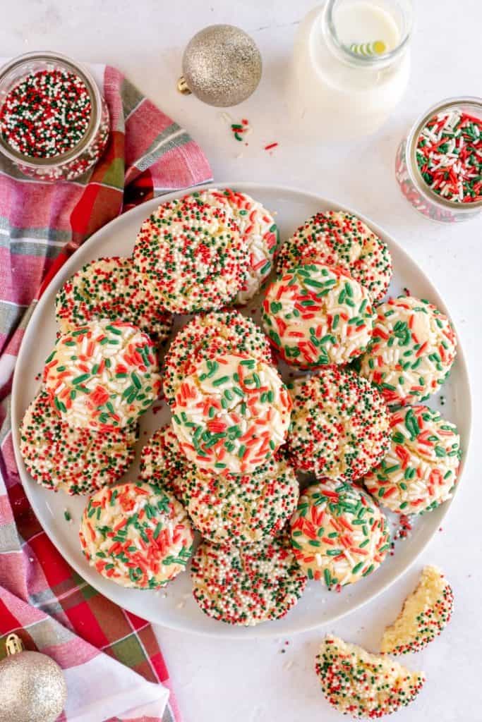 Christmas Sprinkle cookies on a plate with sprinkles surrounding