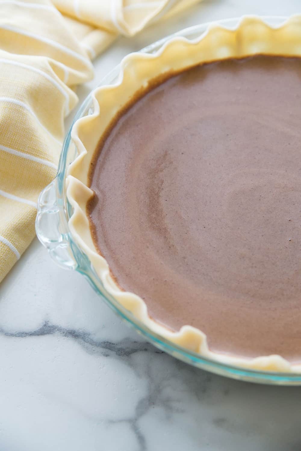 Chocolate Chess Pie batter in an uncooked pie crust and in a clear pie dish.