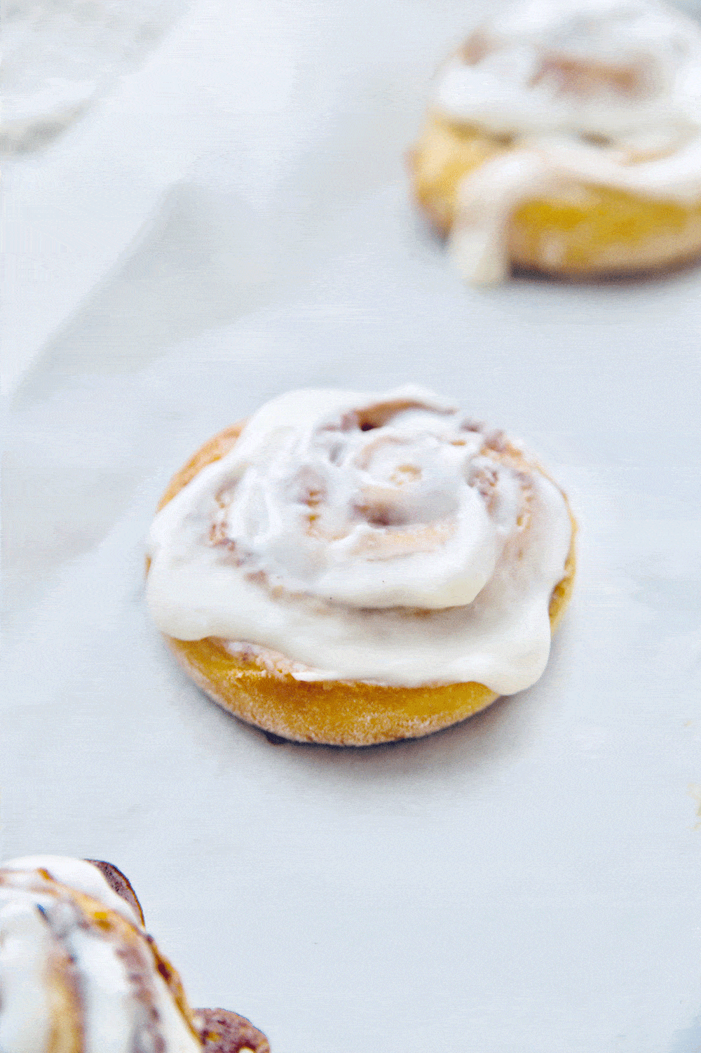 a cinnamon roll on wax paper covered tray freshly frosted