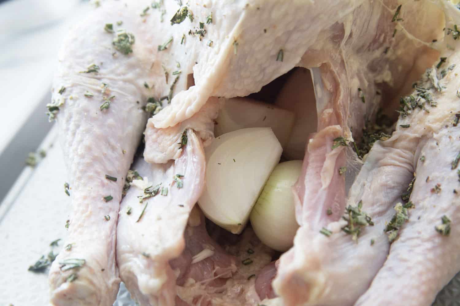 raw turkey cavity with onions and garlic cloves inside