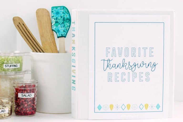 Thanksgiving meal planner binder, white kitchen utensil holder and prepared chopped vegetables in clear plastic containers.