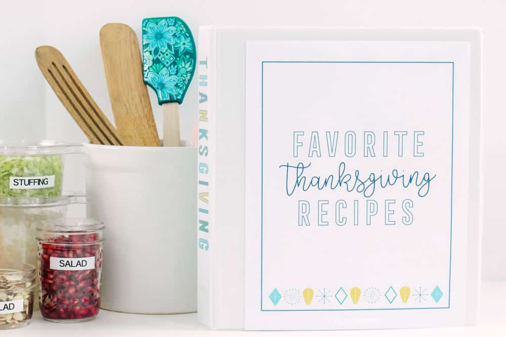 Thanksgiving meal planner binder, white kitchen utensil holder and prepared chopped vegetables in clear plastic containers.