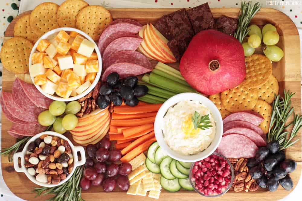 Appetizer board with fruit, cheese, meat, crackers and vegetables.