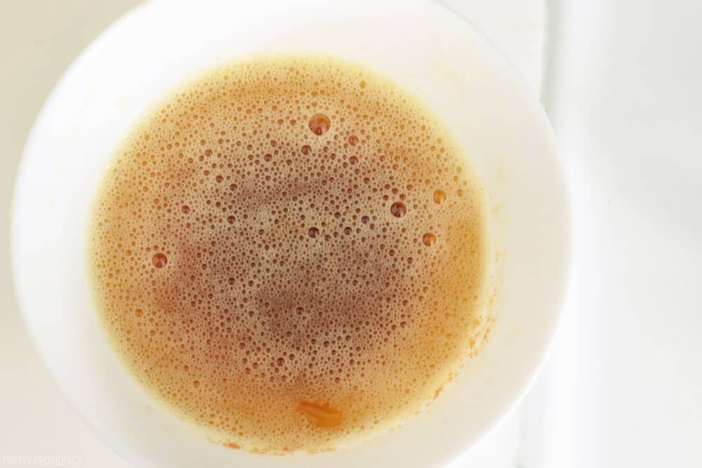 Browned butter in a white bowl with foam on top.