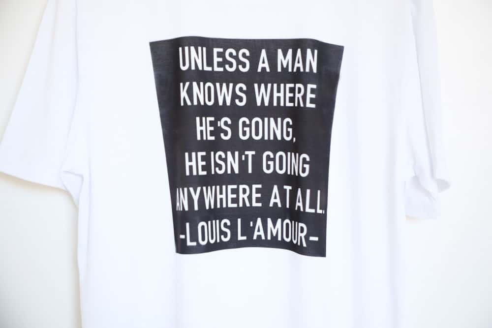 a white shirt with a black square and white text with a Louis L'Amour quote