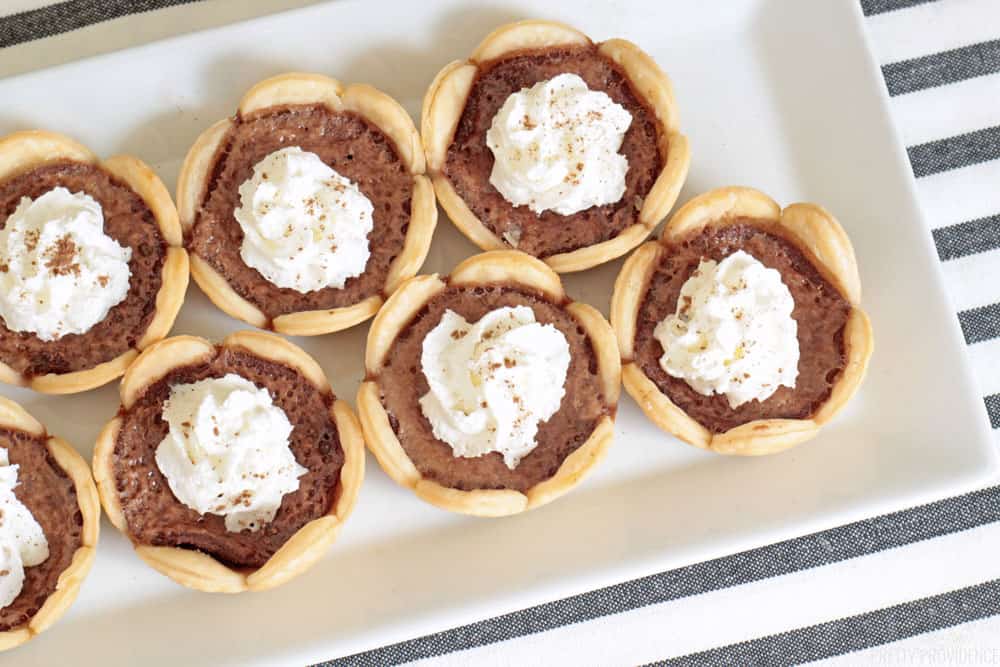 Mini pies with scalloped crust and whipped cream dusted with cocoa powder. 