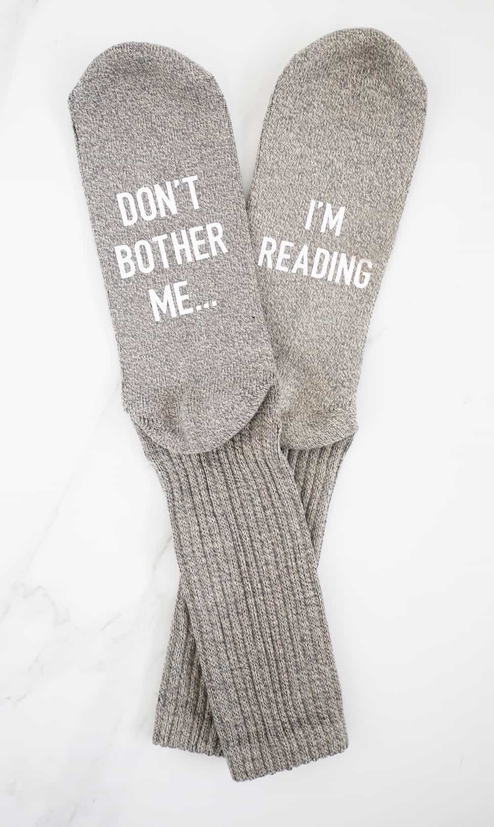 greige socks that say don't bother me i'm reading on a white background