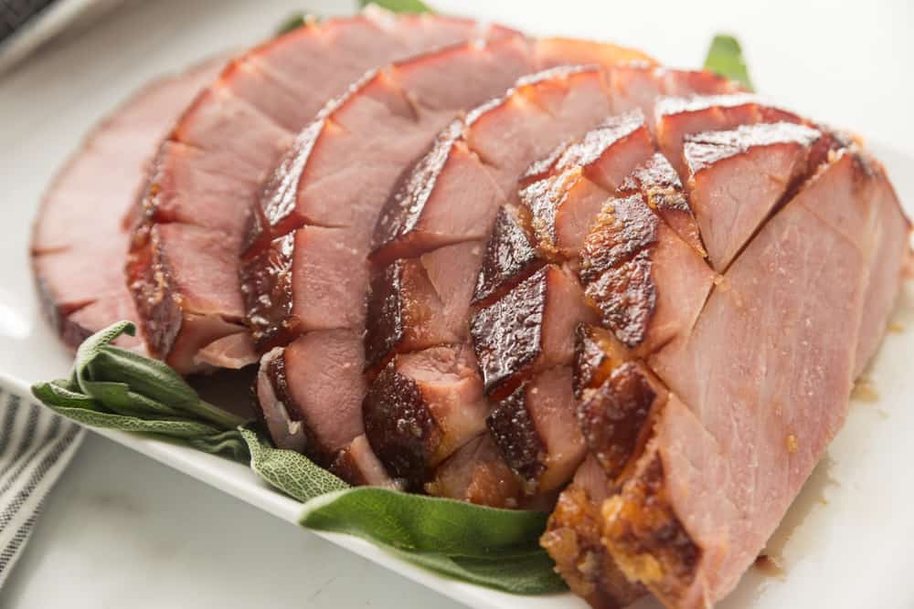 thick ham slices with bay leave garnish on white platter