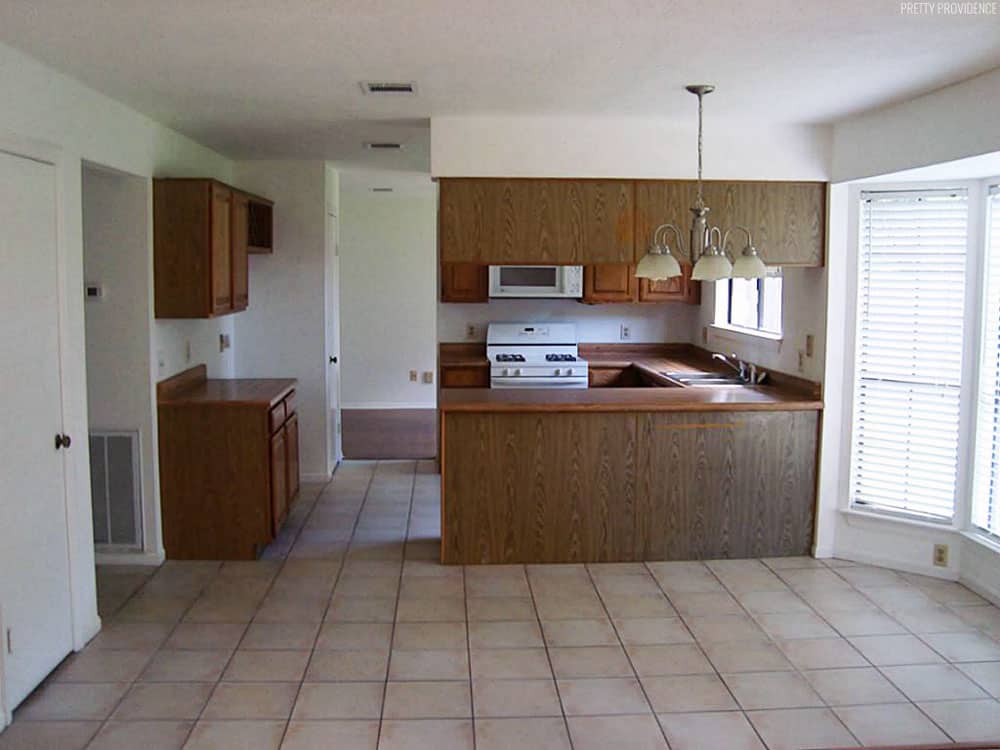 1980's kitchen with brown oak cabinets, tan floor tile and white appliances.