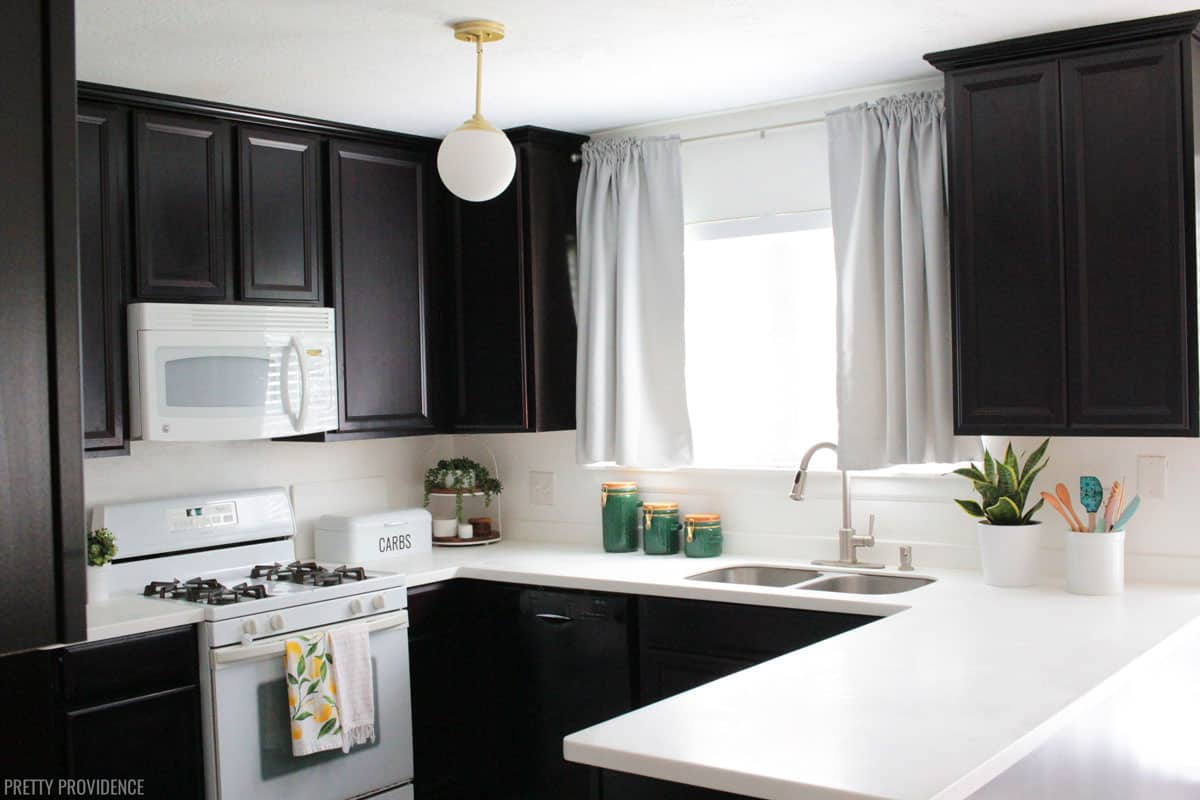 Modern Kitchen Makeover - Kitchen with dark espresso cabinets, white countertops, white appliances and modern lighting.