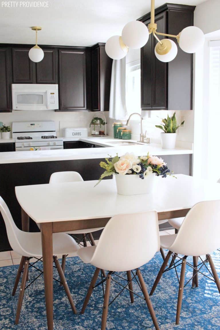 Mid century modern kitchen table espresso legs white table top with eames style chairs and flowers on the table.