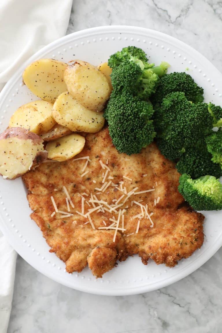 chicken schnitzel on a white plate with broccoli and potatoes