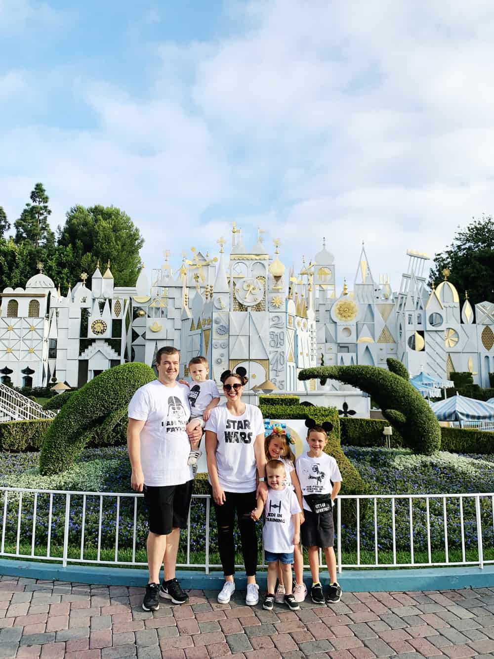 a family at disneyland in front of its a small world wearing matching family star wars shirts